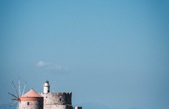 Explore the historic St. Nicholas Fortress and Lighthouse overlooking the Aegean Sea in Rhodes, Greece.